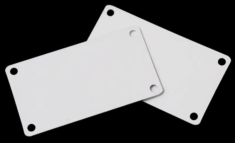 Stacked white metal blanks with mounting holes