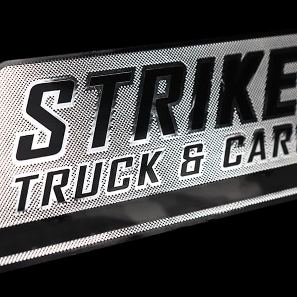 Embossed metal nameplate reading Striker Truck & Car